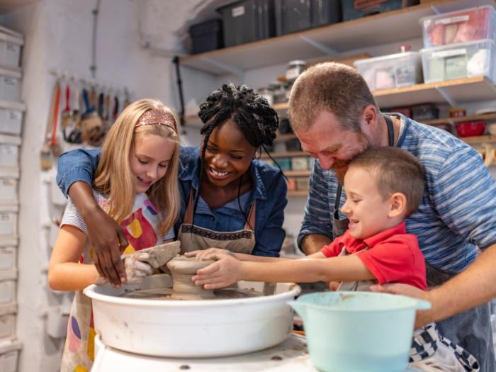 Two adults and two kids doing pottery.